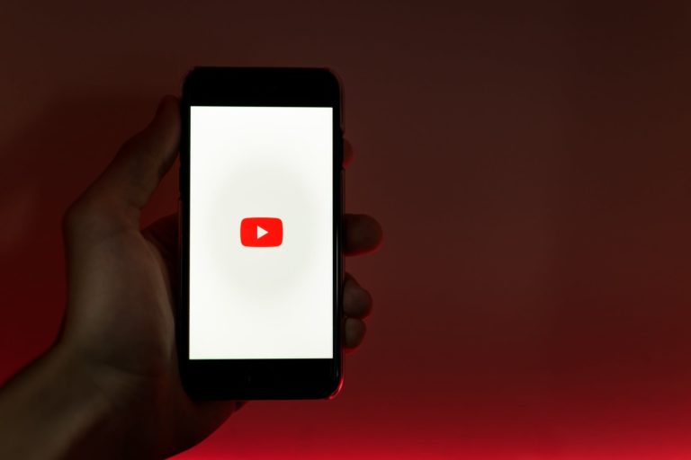 A hand holding a phone showing the Youtube logo
